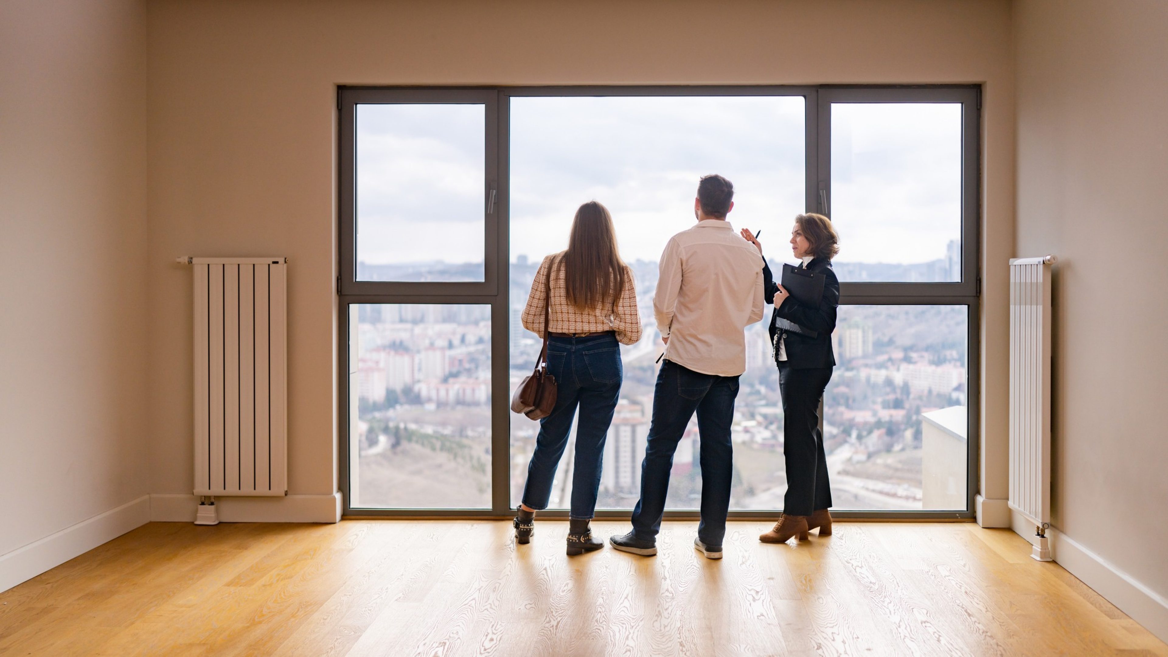 A female real estate agent is showing house to a young couple.