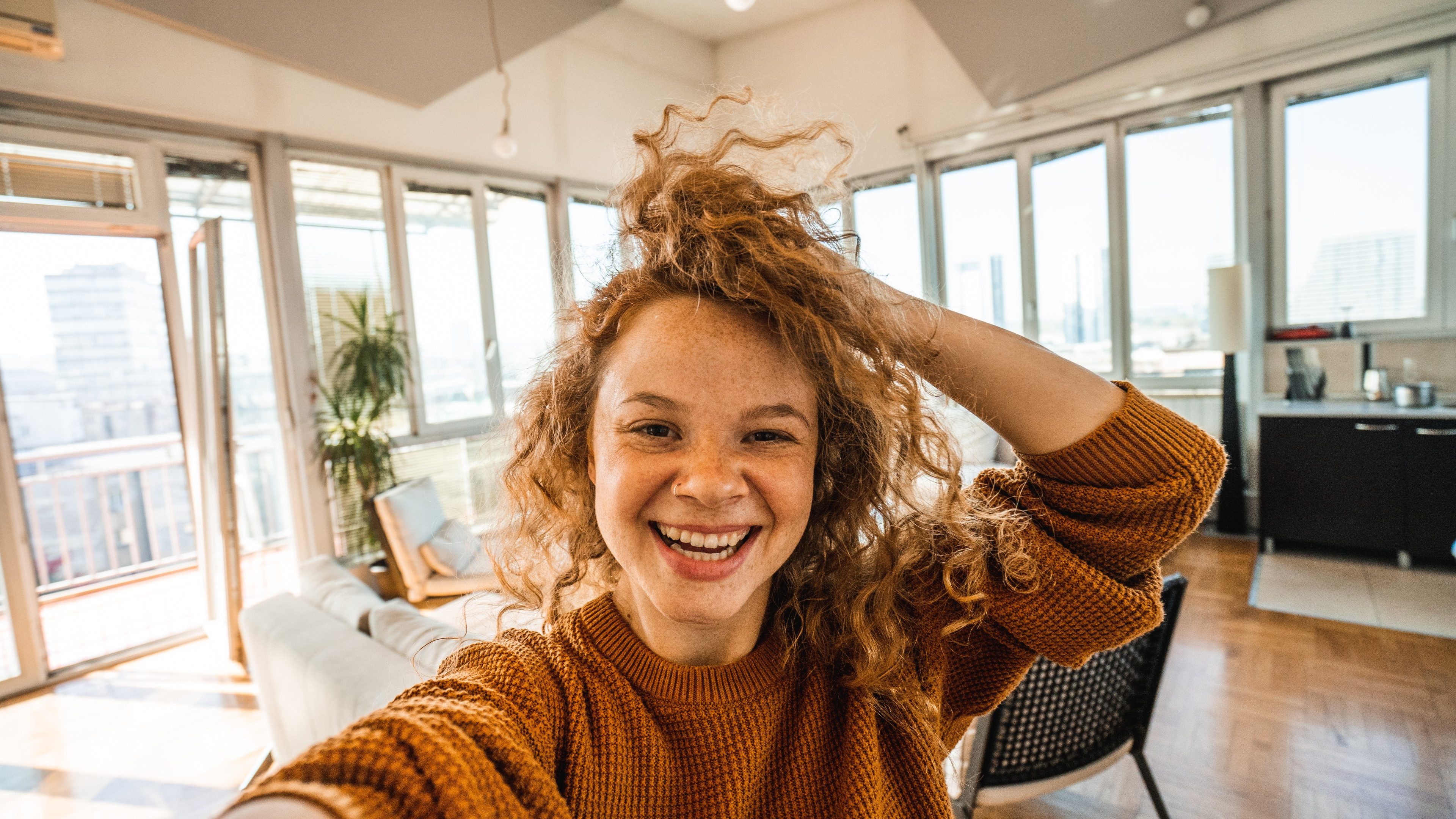 Happy young woman taking selfie in apartment